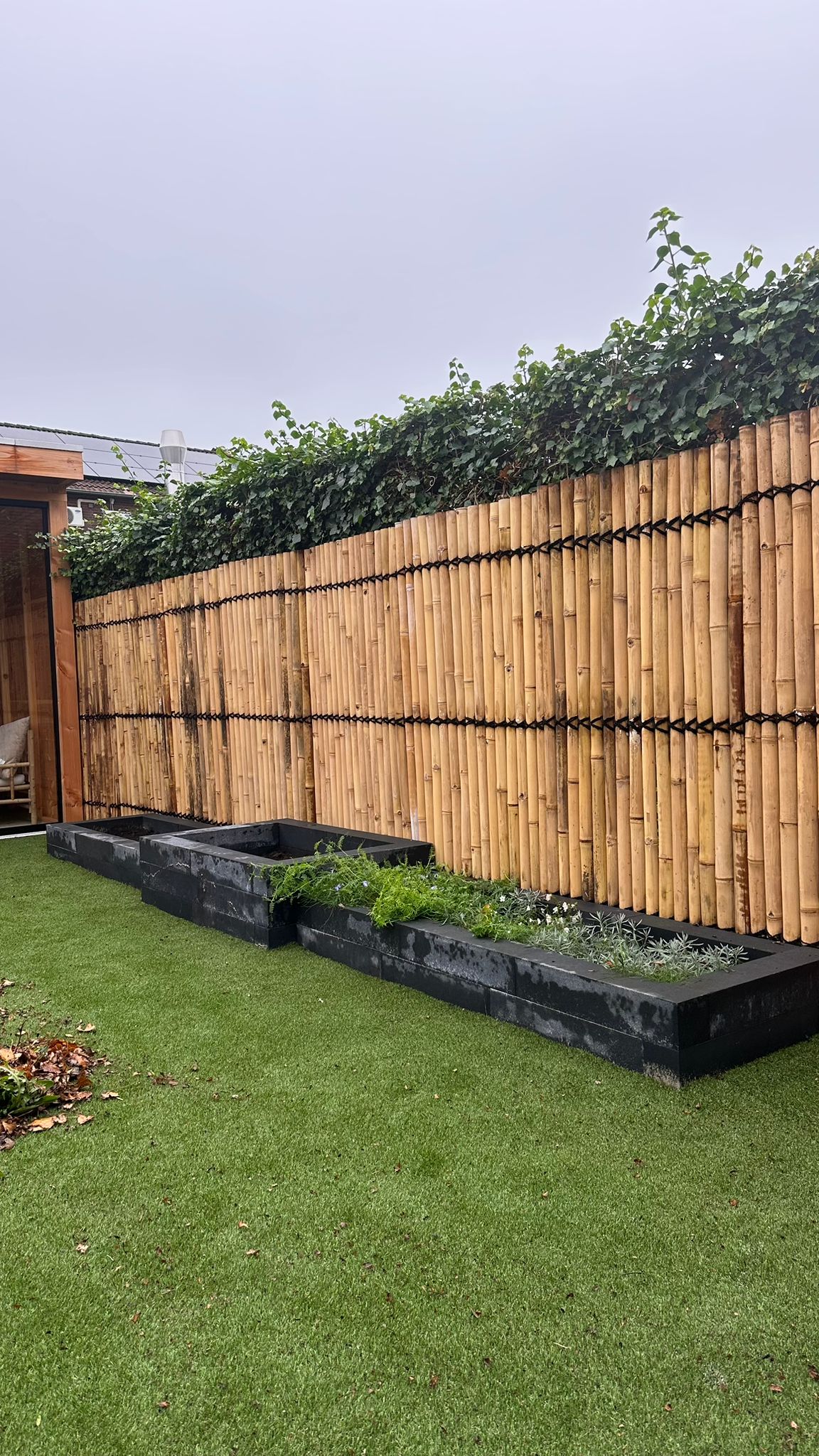 Achtertuin bamboe schutting kunstgras